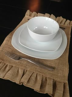 a place setting with white plates and silverware on a burlap placemat