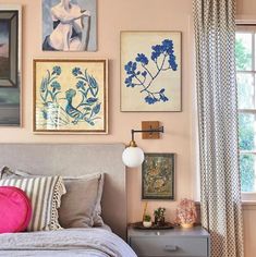 a bedroom with pink walls and pictures on the wall above the bed, along with two nightstands