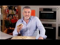 a man standing in front of a counter holding a pizza on it's side