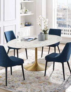 a dining room table with blue chairs and a rug on the floor in front of it