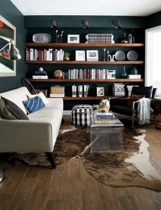 a living room filled with furniture and a cow hide rug on top of a hard wood floor