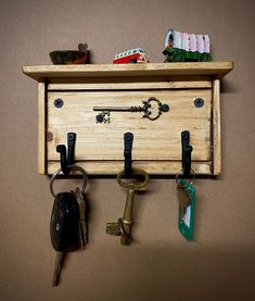 a wooden drawer with keys hanging from it's sides and several other key holders on the wall