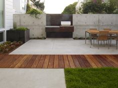 an outdoor patio with table and chairs next to a fenced in area that has grass on both sides