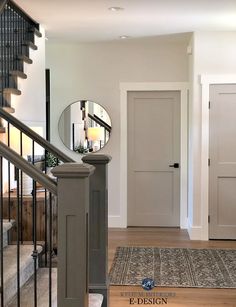 an entry way with stairs and a round mirror on the wall next to a door