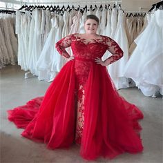 a woman in a red dress standing next to some dresses