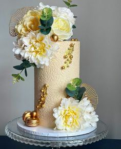 a white and gold wedding cake with flowers on top