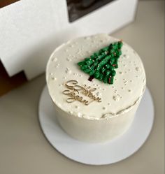 there is a white cake with green decorations on the top, and a small christmas tree decoration on the bottom