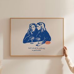 a woman holding up a framed poster with two women on it