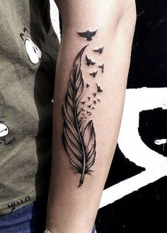 a black and white photo of a tattoo with a feather on it's arm