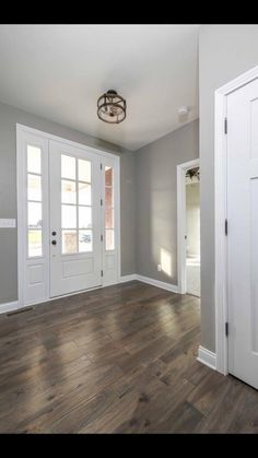 an empty room with white doors and wood flooring in the center is pictured here