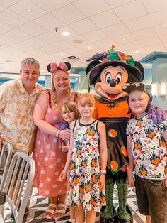 a group of people standing next to each other in front of a mickey mouse mascot