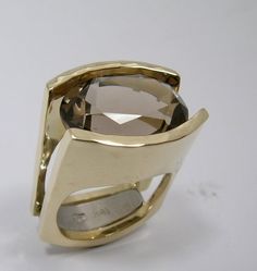 A simply stunning engagement ring that is made to last forever. Comes with a lifetime warranty. Very chunky looking on a size 4 finger. I can keep proportions the same for larger ring sizes by using a larger stone. I design and create your engagement ring with love in my Waterton based studio.  Specific details: 18 kt. yellow  8 mm to 14mm wide band 12 x 16 mm oval smoky quartz High Polish finish with hammer forged detail I will  craft the ring in my goldsmith workshop. Made to measure in all ring sizes. Ready to ship in 6 to 8 weeks. Please have your ring size measured at your local jeweller so you will receive the right size.  Other options are possible. I am happy to send you the price estimate! * Choose the color you prefer. The ring can also be created out of yellow or rose gold.  * C Luxury Hand Cast Engagement Rings, Luxury Artisan Hallmarked Rings, Luxury Polished Finish Ring, Luxury Modern Rings For Jewelry Making, Luxury Contemporary Ring Jewelry, Luxury Brushed Finish Engagement Rings, Luxury Untreated Modern Rings, Luxury Gold Modernist Rings, Luxury Modern Hallmarked Rings