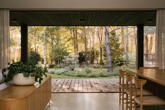 a wooden table sitting under a window next to a forest filled with lots of trees