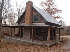 an old log cabin with a bicycle parked on the front porch and covered porch area