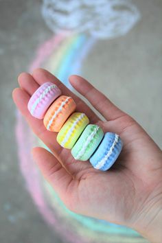 a hand holding four small colorfully decorated macaroni shells