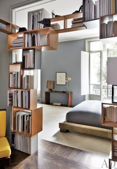 a book case with books on it in the middle of a room next to a bed