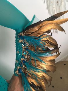 a woman wearing a blue and gold costume with feathers on it's chest,