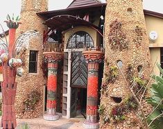 an elaborately designed house with red and green decorations on the front door, surrounded by greenery