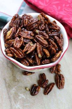 a bowl filled with pecans sitting on top of a table next to a cloth