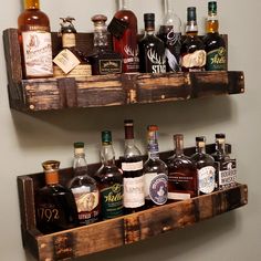 two wooden shelves filled with different types of liquor bottles on top of eachother