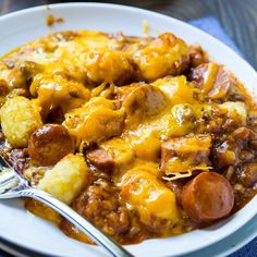 a white plate topped with sausage and tater tot casserole next to a fork