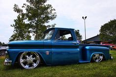 a blue truck parked on top of a lush green field