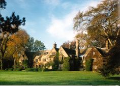 an old house with ivy growing on it's sides and trees in the foreground