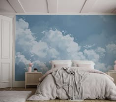 a bedroom with blue sky and white clouds painted on the wall behind it is a bed