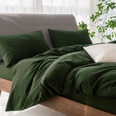 a bed covered in green sheets and pillows