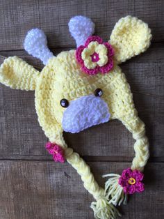 a crocheted dog hat with flowers on it's ears and nose is laying on a wooden surface