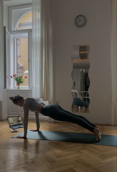 a woman is doing yoga in front of a laptop