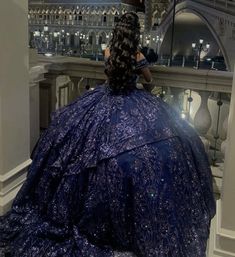 a woman in a blue ball gown sitting on a balcony