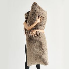 a woman is wrapped up in a large furry animal blanket and posing for the camera