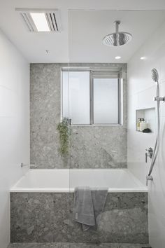 a bathroom with a bathtub, shower head and window