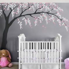 a baby's room with a tree painted on the wall and a crib next to it