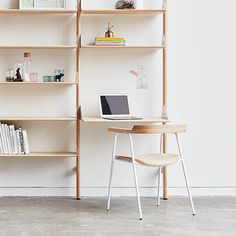 a laptop computer sitting on top of a wooden desk next to a book shelf filled with books