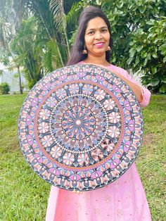 a woman is holding up a colorfully decorated round object in her hands and smiling at the camera