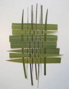 an abstract piece of art made out of green strips of grass and sticks on a white wall