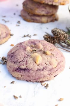 three cookies are sitting on a table next to some dried herbs and lavenders in the background