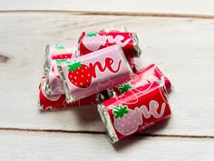 three strawberry milk chocolate bars on a white wooden surface with the word love painted on them