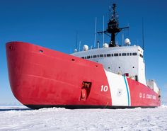 a large red and white boat sitting on top of snow covered ground