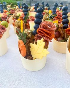 small pots filled with fruit and vegetables on top of a white cloth covered tablecloth