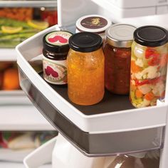 jars filled with food sit in the open refrigerator door