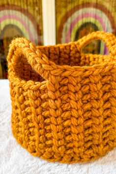 an orange crocheted basket sitting on top of a white blanket