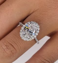 a woman's hand with a diamond ring on it and the center stone is surrounded by diamonds