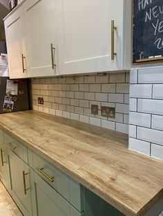 a kitchen with white cabinets and wooden counter tops in front of a chalkboard that says happy new year