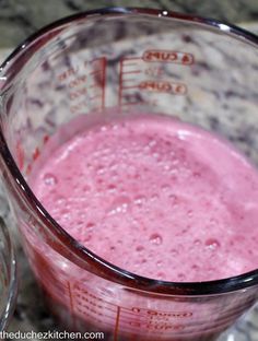 a blender filled with pink liquid on top of a counter