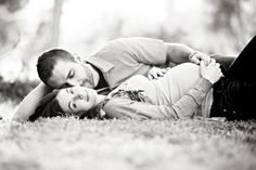 a man and woman laying on the ground in black and white with their arms around each other