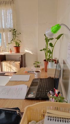 a laptop computer sitting on top of a wooden desk next to a potted plant