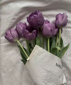 purple tulips sitting on top of a white sheet